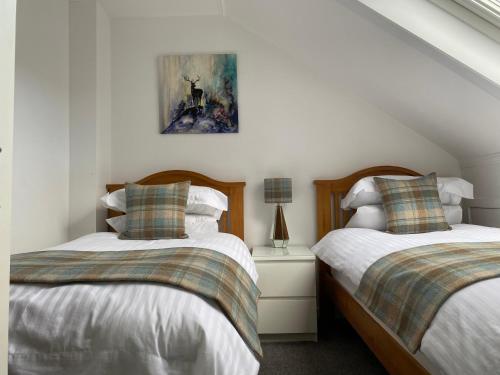 a bedroom with two beds and a picture on the wall at Innisfree Self Catering Apartment, Banavie, Fort William in Fort William