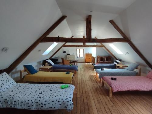 Una habitación abuhardillada con varias camas y sofás. en Le refuge d'Athéna, en Chaussy