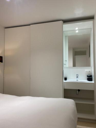 1 dormitorio con cama con espejo y lavamanos en Nieuwpoort in 't zonneke - appartement met terras en Nieuwpoort