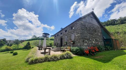 um edifício de pedra com uma mesa e bancos num quintal em Pousada Cantelli em Bento Gonçalves