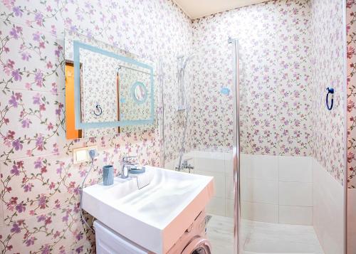 トビリシにあるHB apartments Vazha Pshavelaのピンクの花の壁紙を使用したバスルーム(シンク、シャワー付)