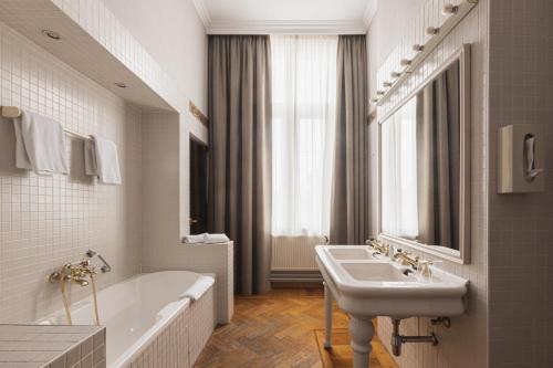 a bathroom with a tub and a sink and a bath tubermottermott at Hotel Amfora in Poperinge