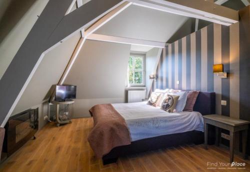 a bedroom with a bed and a tv in it at La Ragotière in Froyennes