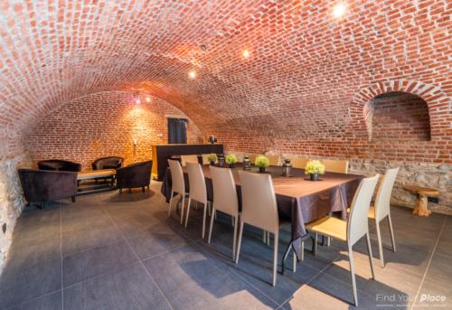 a dining room with a brick wall and a table and chairs at La Ragotière in Froyennes