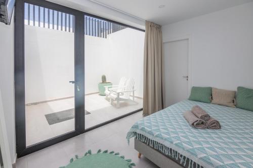 a bedroom with a bed and a large window at Cascasas The Green Apartment in Corralejo