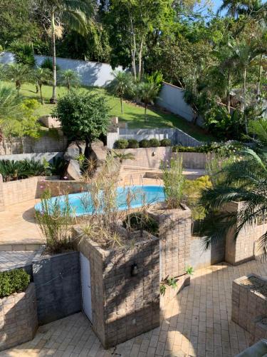 um jardim com piscina e árvores em Pousada DRIRIOS HOUSE em Jaraguá do Sul