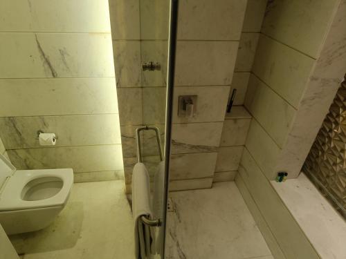 a bathroom with a shower with a toilet and a sink at Boulevard by Design Hotel Chennai in Chennai