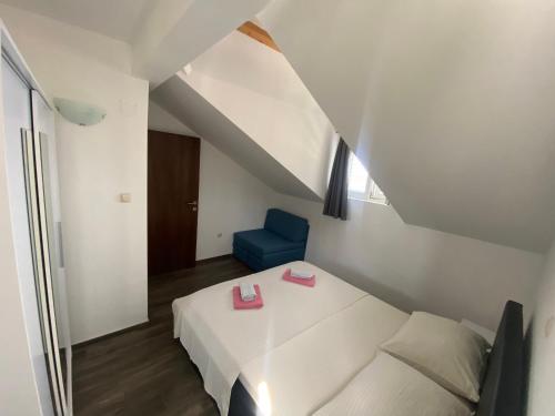 a bedroom with a white bed and a blue chair at GUESTHOUSE RUZA SOBRA apartments in the attic of the house in Sobra