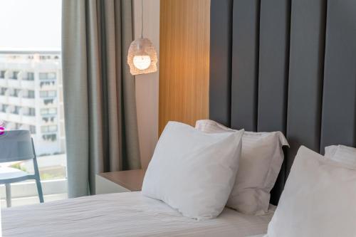 a bedroom with a bed with white pillows and a window at Napa Mermaid Hotel & Suites in Ayia Napa