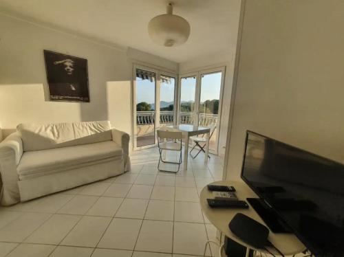 - un salon avec un canapé, une télévision et une table dans l'établissement Bel Appartement avec Vue Mer - Picaud, à Cannes