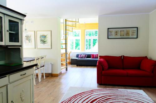 a living room with a red couch and a kitchen at Villa Dębowa in Polanica-Zdrój