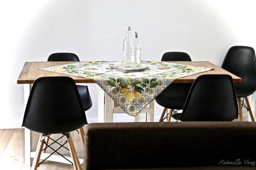 einen Esstisch mit schwarzen Stühlen und einem Tischtuch in der Unterkunft Casa Maddy Amalfi Coast in Atrani