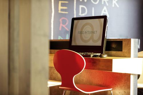 a red chair in front of a desk with a computer at ibis Hotel Brussels Airport in Diegem