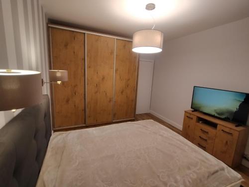 a bedroom with a bed and a flat screen tv at Fajny apartament z parkingiem, obok metra. in Warsaw