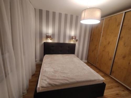 a bedroom with a bed and a light fixture at Fajny apartament z parkingiem, obok metra. in Warsaw