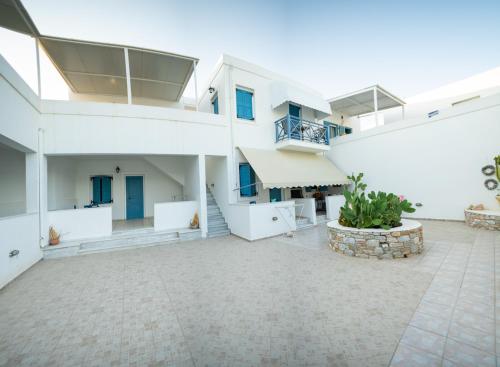 einen großen Innenhof in einem weißen Gebäude mit einer Terrasse in der Unterkunft Manos Rooms in Megas Gialos - Nites