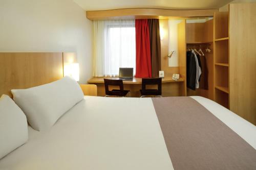 Schlafzimmer mit einem Bett und einem Schreibtisch mit einem Computer in der Unterkunft ibis Hotel Brussels Airport in Diegem