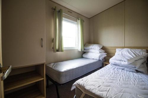 Ліжко або ліжка в номері 6 Berth Caravan For Hire With Wifi At Seawick Holiday Park In Essex Ref 27025hv