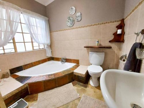 a bathroom with a bath tub and a toilet at InnibosRus Self-catering in White River