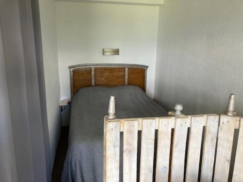 a small bedroom with a bed with a wooden headboard at Studio face aux montagnes Font-Romeu in Font-Romeu-Odeillo-Via