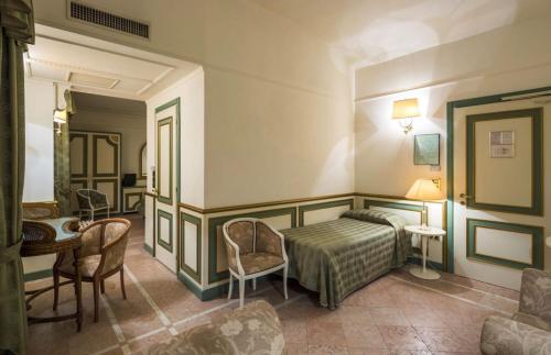 Grand Hotel Terme في ريولو تيرمي: غرفة نوم بسرير وطاولة وكراسي