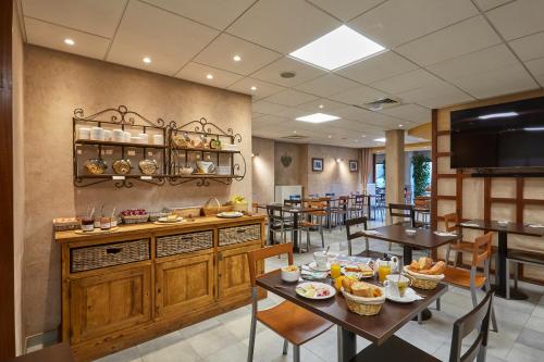 a dining room with tables and chairs in a restaurant at Cit'Hôtel Le National in Cluses