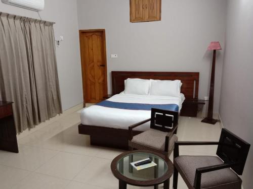 Almas Hotel Sylhet في Debpur: غرفة نوم بسرير وكرسي وطاولة