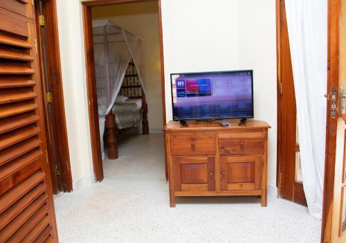 a television on a wooden dresser in a room at Tembo Court Apartments in Malindi