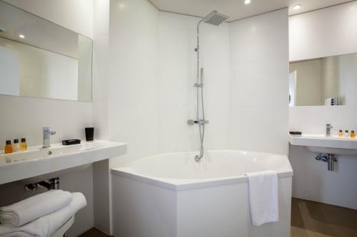 La salle de bains blanche est pourvue d'une baignoire et d'un lavabo. dans l'établissement villa ciel et mer, à Pyla-sur-Mer