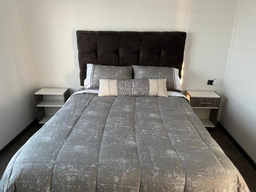 een groot bed in een slaapkamer met 2 nachtkastjes bij LETICE LODGE Chillán in Chillán