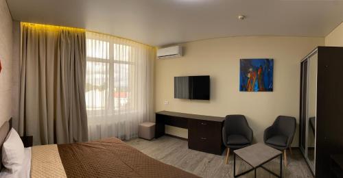 Hotel Atmosphere في بولتافا: غرفة نوم بسرير ومكتب مع كرسيين