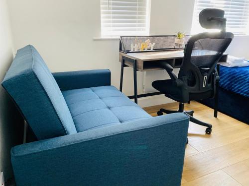 Sofá azul en una habitación con escritorio y silla en KENILWORTH STUDIO * GROUND FLOOR * PARKING, en Kenilworth