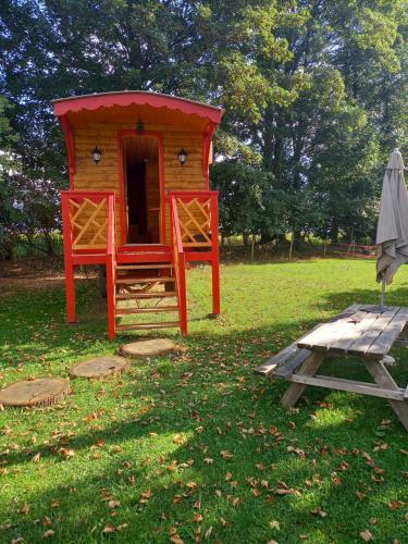 ein rotes Spielhaus mit einem Picknicktisch und einem Regenschirm in der Unterkunft Les Insolites de Nini in Grainville-Ymauville