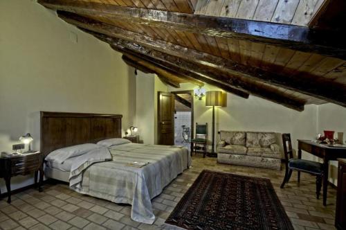 Castello di Altomonte في آلتومونتيه: غرفة نوم بسرير ومكتب واريكة