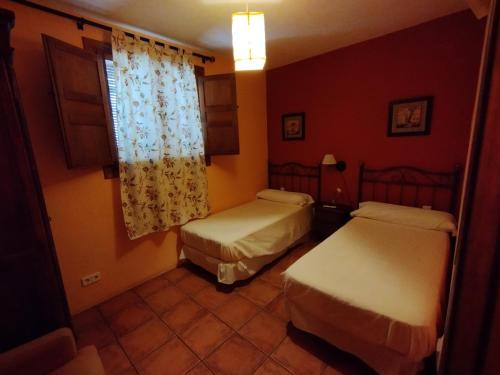 a hotel room with two beds and a window at La Casa de los Gatos in Condemios de Abajo