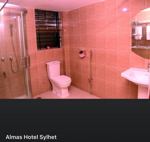 La salle de bains rose est pourvue de toilettes et d'une douche. dans l'établissement Almas Hotel Sylhet, à Debpur