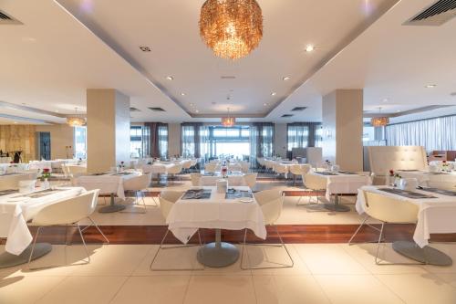 a restaurant with white tables and chairs and a chandelier at Napa Mermaid Hotel & Suites in Ayia Napa