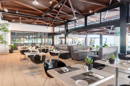 a restaurant with tables and chairs and windows at Napa Mermaid Hotel & Suites in Ayia Napa