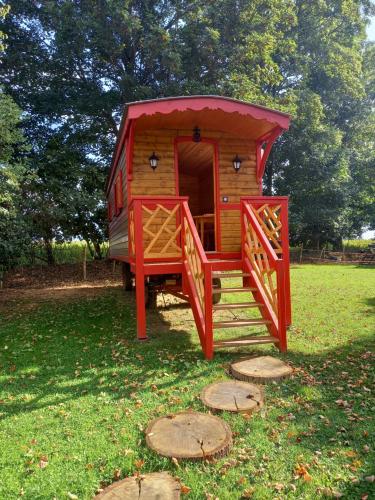 ein rotes Spielhaus auf einem Feld mit einer Veranda in der Unterkunft Les Insolites de Nini in Grainville-Ymauville