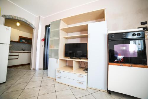a kitchen with white cabinets and a tv at La tua Vacanza al Mare in Borghetto Santo Spirito