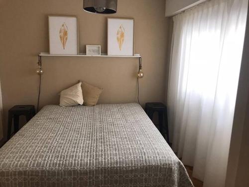 1 dormitorio con 1 cama con colcha blanca y ventana en El lugar en Palermo Chico en Buenos Aires