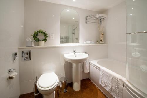 La salle de bains blanche est pourvue d'un lavabo, de toilettes et d'une baignoire. dans l'établissement The King William IV Country Inn & Restaurant, à Sedgeford