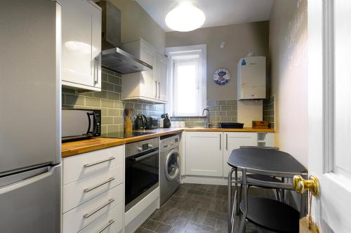 a kitchen with white cabinets and a dishwasher at Cosy near centre Edinburgh apartment in Edinburgh