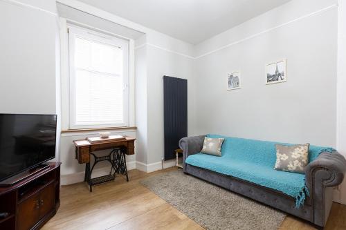 a living room with a couch and a television at Cosy near centre Edinburgh apartment in Edinburgh