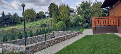 a garden with a stone wall and a fence at Apartamenty Nad Stawem in Powidz