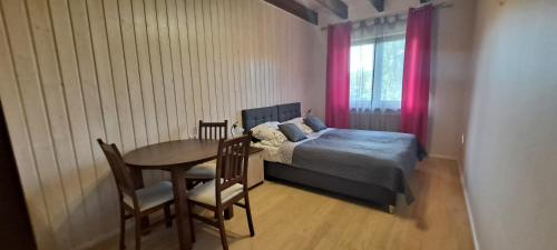 a bedroom with a bed and a table and chairs at Apartament Nad Stawem in Powidz