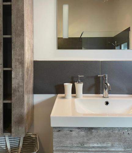 une salle de bain avec un lavabo blanc et un miroir dans l'établissement Villa Alivu belle piscine chauffée, à Bonifacio