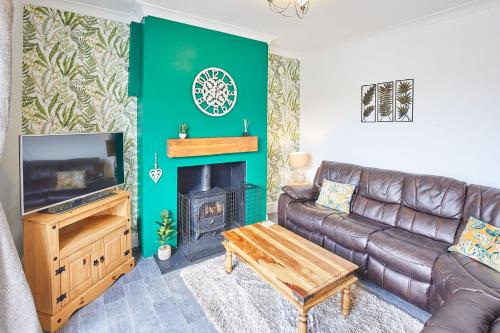 a living room with a leather couch and a fireplace at Host & Stay - Seagull Cottage in Bridlington