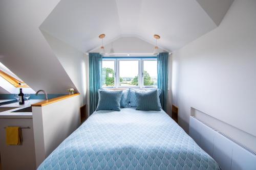 um pequeno quarto com uma cama e uma janela em The Loft at The Little Elms em Motcombe