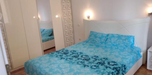 1 dormitorio con cama azul y espejo en Lovely condo next to salt room, bus station, en Skopje